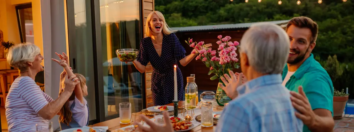 Personen sitzen abends beim Abendessen auf einer Terrasse