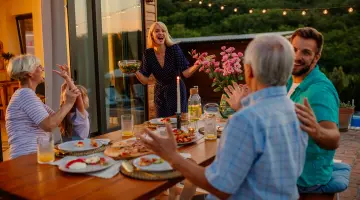 Personen sitzen abends beim Abendessen auf einer Terrasse