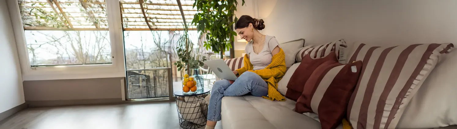 Frau sitz auf einer Couch mit Laptop