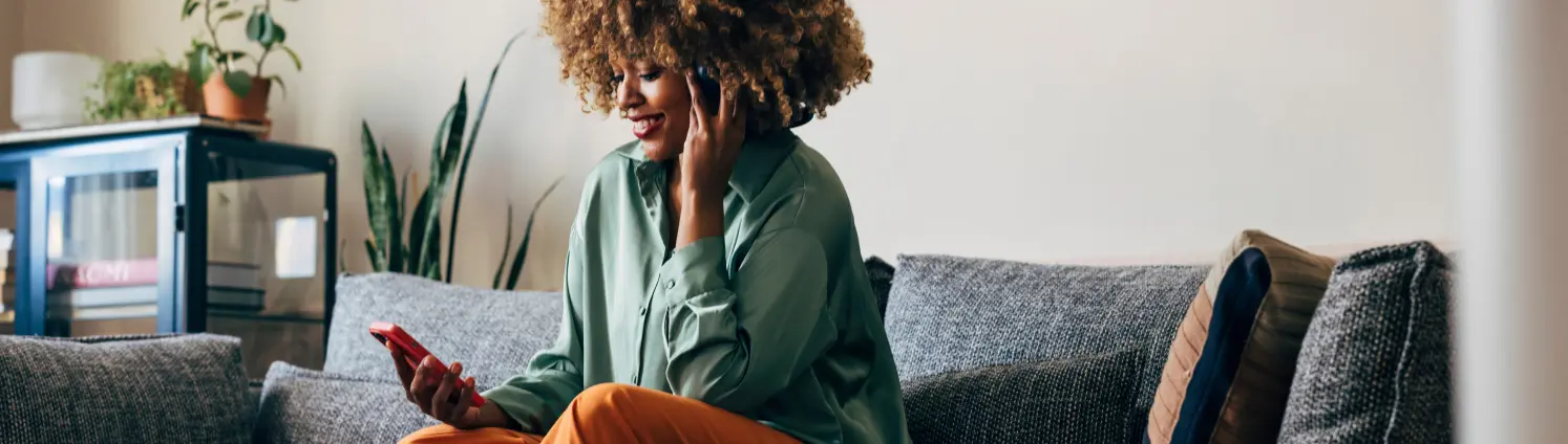 Eine junge Frau sitzt zu Hause mit einem Smartphone