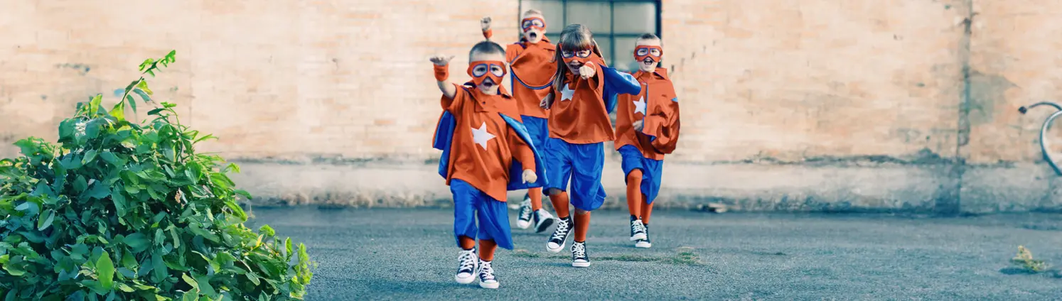 Kinder die als Helden in orange-blauen Kostümen verkleidet