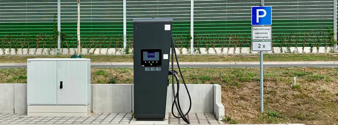 Eine schwarze Schnelladesäule steht an einem Parkplatz