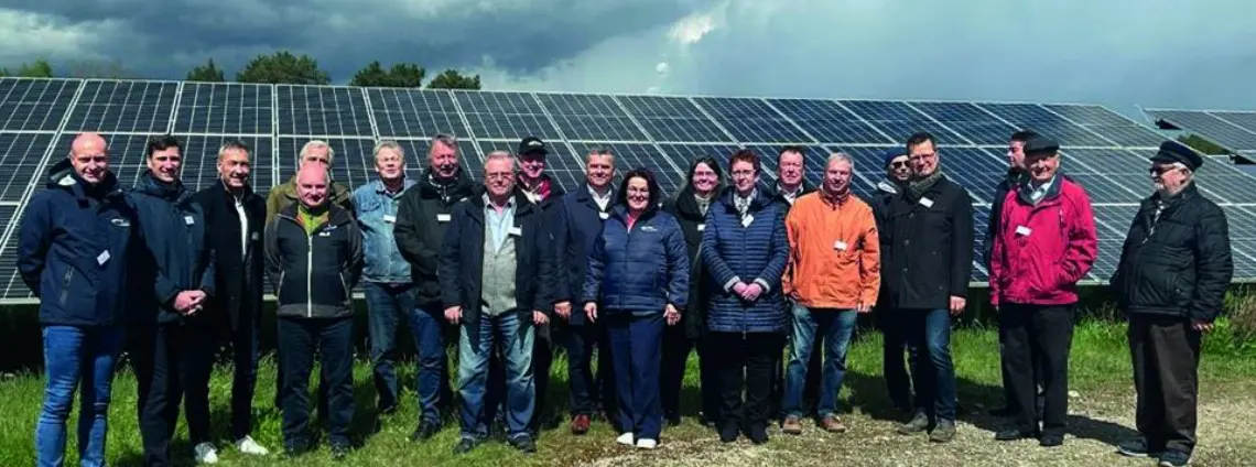 Mehrere Personen in Jacken stehen vor einem Solarpark