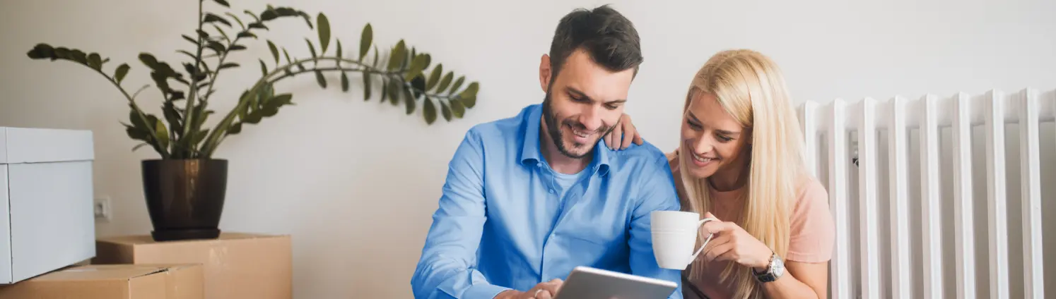 Glückliches Paar mit digitalem Tablet beim Kaffeetrinken in der neuen Wohnung